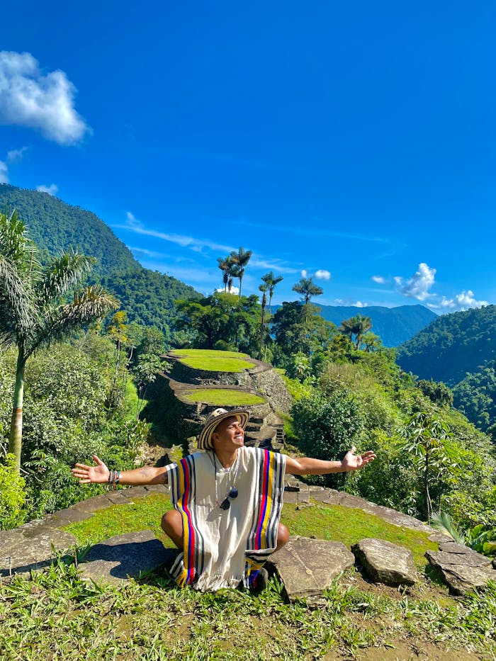 Traveler sits at ancient ruins surrounded by tropical jungle under a clear blue sky.